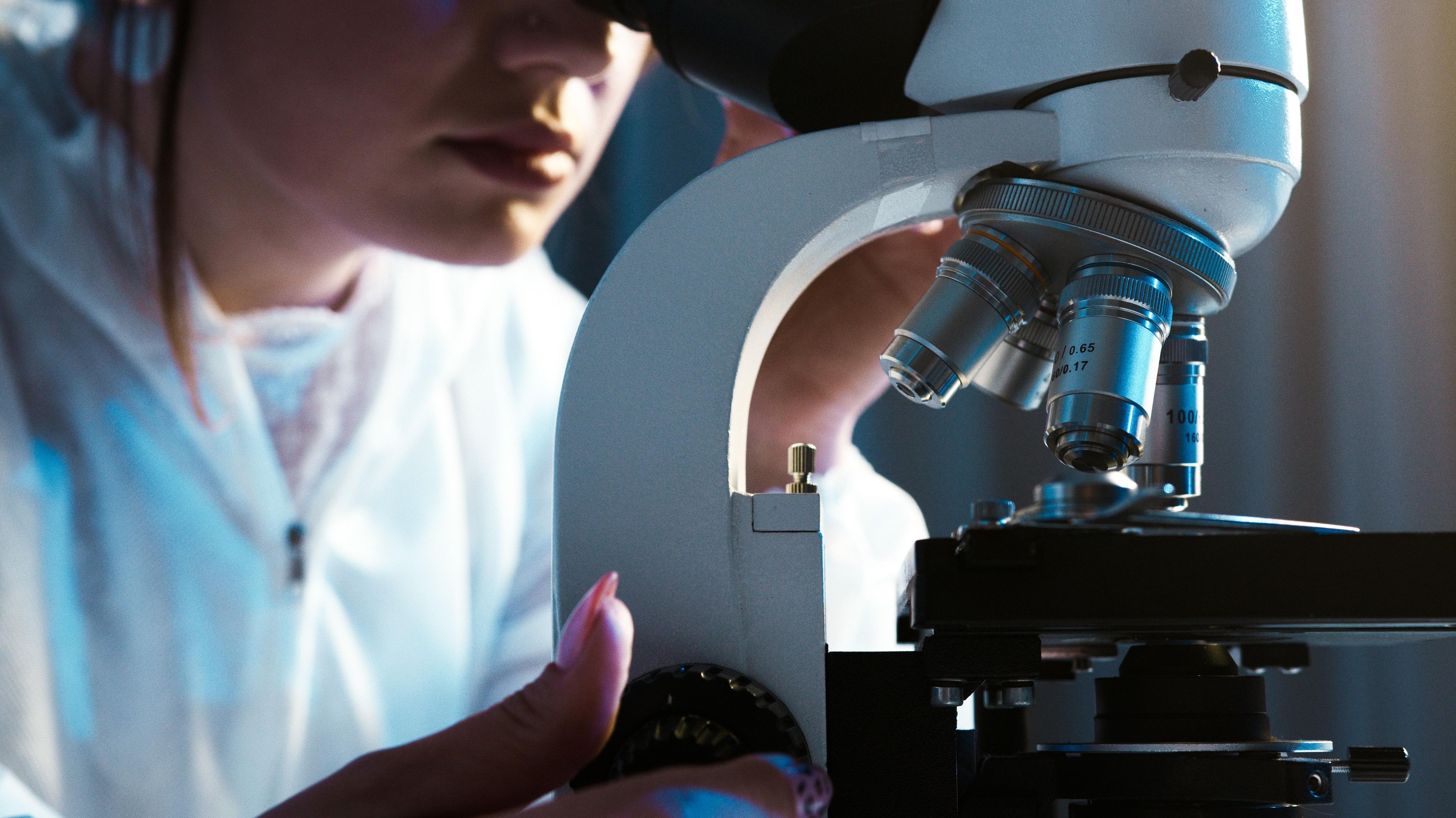 Laboratory professional using a real optical microscope